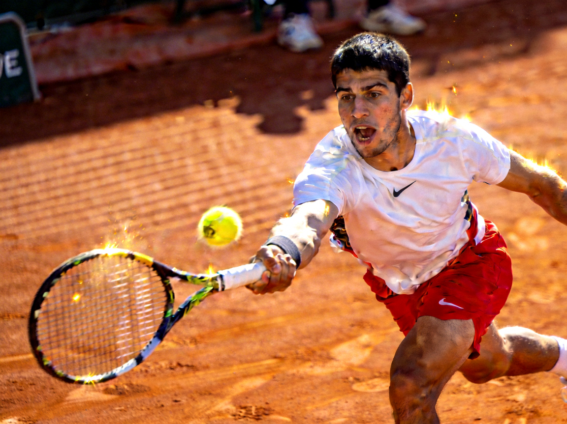 网球运动员卡洛斯·阿尔卡拉斯在红土场击球 - 年轻有活力的表情